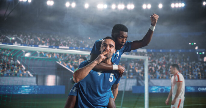 Black and Middle Eastern Male Soccer Teammates Celebrate a Vital Goal at the Net During a Professional International Tournament Match, With One Player on His Teammate&rsquo;s Back as a Rival Walks Away.