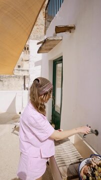 Static video of a woman washing fresh vegetables on her terrace in southern Italy. Mediterranean everyday life, simple outdoor routine, calm domestic moment, slow living atmosphere and peaceful