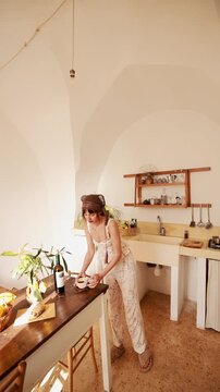 woman enjoying a quiet moment in a Mediterranean-style kitchen. Natural light, simple interior, fresh lemons and wine on the table, calm everyday life and peaceful slow living atmosphere