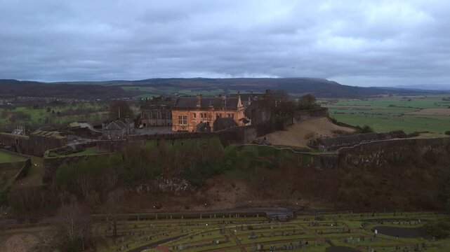 Stirling Scotland city skyline drone flyover and mountains in the distance. Clouds cover the sky, creating an atmosphere in the Scottish highlands
