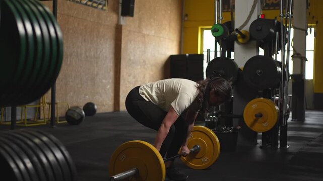 Strong woman deadlifting a heavy barbell in the gym