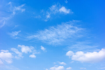 Fototapeta premium This bright, horizontal shot captures a breathtakingly clear blue sky adorned with soft, wispy cirrus clouds and scattered white cumulus formations during a sunny day.