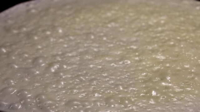 Cooking process of batter transforming into a golden-brown crepe on a hot skillet, showcasing the bubbling surface and gradual browning in a kitchen setting
