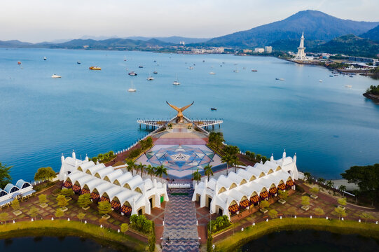 Photo aerial view of Dataran Lang, also known as Eagle Square, a prominent landmark featuring a massive eagle statue and white-roofed pavilions by the scenic bay of Langkawi, Malaysia