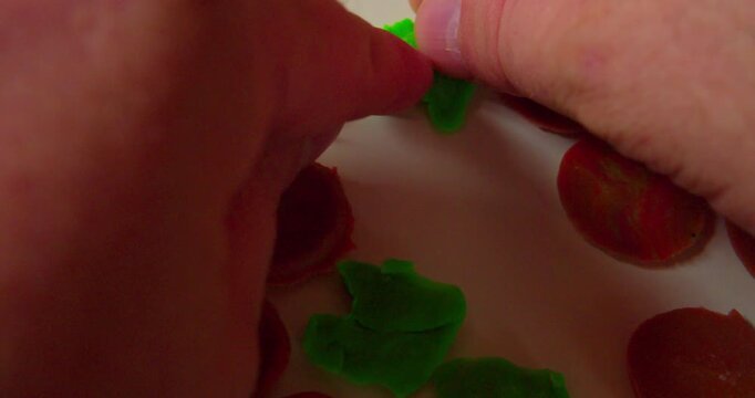 Hands of a designer placing abstract design composed of solid plastic fragments on a surface, first-person perspective, close-up.