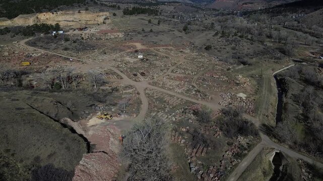 Quarry yard patterns near N Foothills Hwy by Hygiene with stone stacks arranged along winding dirt paths open rural parcels. Quarry textures, rugged slabs, dusty soil, midday light, Longmont, CO