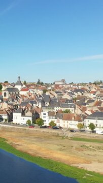 Scenic aerial view of La Charite sur Loire with traditional rooftops and the Loire river under a clear blue sky. Picturesque historic town in central France.