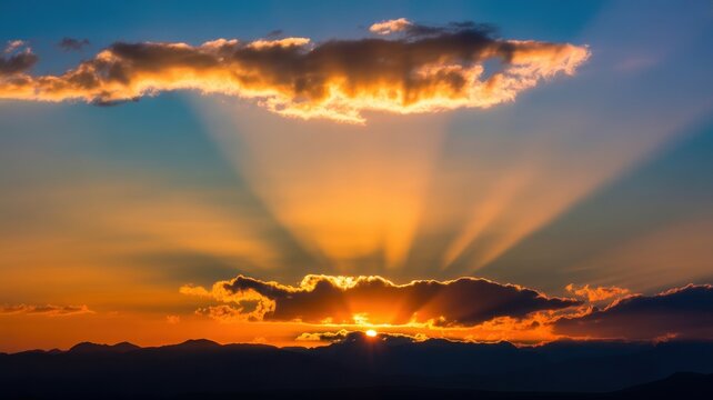 Stunning sunset with golden sunrays piercing through clouds over mountain landscape.