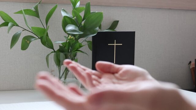 Woman Opening Hands in Prayer with Bible in Background, Faith and Spiritual Devotion Concept