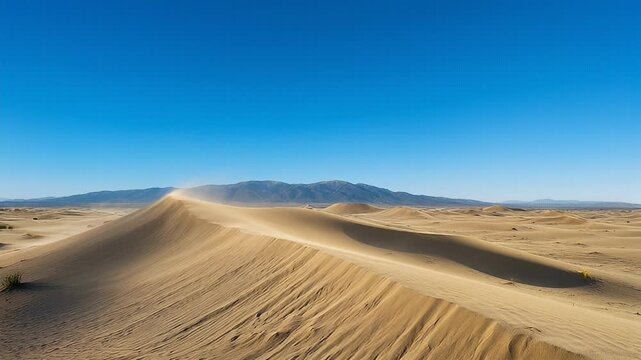 Vast desert landscape with rolling sand dunes, distant mountains, and clear blue sky