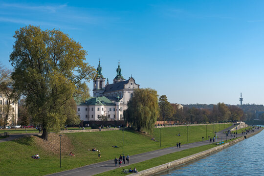 Basilica of St. Michael the Archangel in Krakow with people relaxing on the riverbank.
