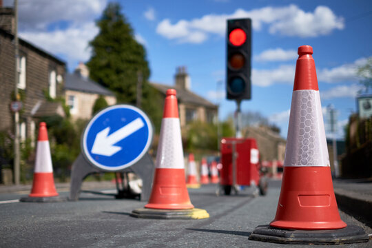 A red signal on a traffic light behind a series of road cones marking out roadworks