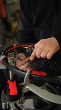 A racket technician expertly installs strings on a tennis racket using advanced equipment