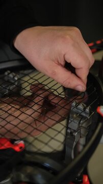 A professional stringer meticulously restrings a tennis racket with a precision machine