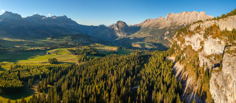 Aerial panoramic view of the Devoluy massif in the French Alps, Hautes-Alpes, France. Scenic mountain landscape and sunlit alpine valley with limestone cliffs, forest, and meadows