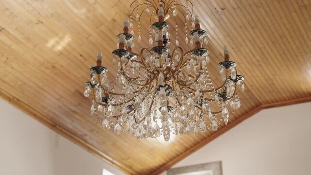 Elegant crystal chandelier sparkling on wooden ceiling in vintage room motion