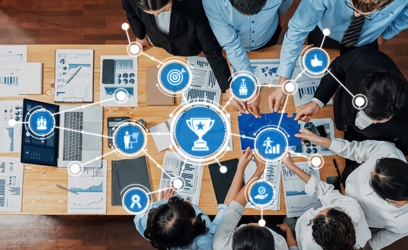 A dynamic overhead view of a business meeting, showcasing professionals collaborating on project planning and data analysis with digital tools and graphs to drive success. Amity