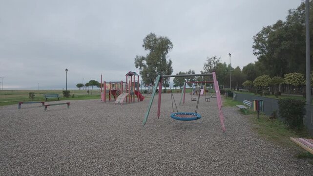 Large fenced playground with slides and swings in empty park