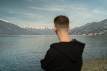 Fototapeta premium Traveler standing back view looking at Alpine mountains and Lake Como landscape in Lombardy Italy.