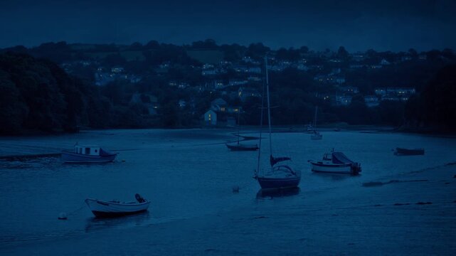 Estuary Landscape With Boats And Houses Lit Up In The Evening
