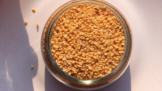 Yellow Lentil/ Moong Dal Filled In Glass Bowl Table Top Spin isolated on white background