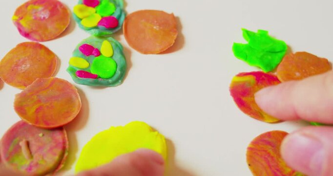 Hands of a designer placing abstract design composed of solid plastic fragments on a surface, first-person perspective, close-up.