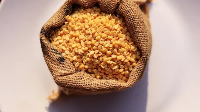 Yellow Lentil/ Moong Dal Filled in Jute Sack Table Top Spin isolated on white background