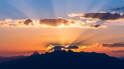 Obraz premium Sunset over a mountain range with clouds and sun rays