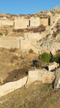 Stone fortress ruins and defensive walls of Acrocorinth on a rugged hillside in Greece, bathed in warm sunlight.