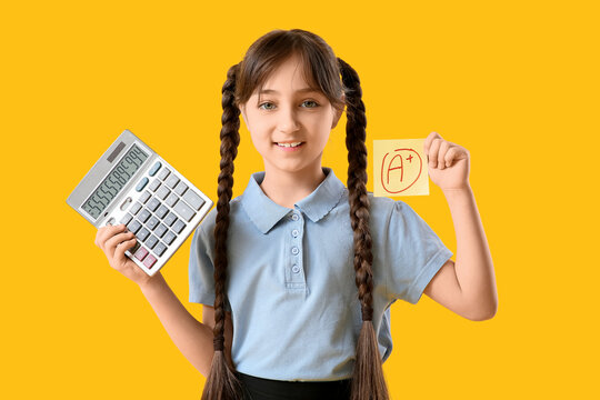 Happy schoolgirl holding calculator and sticky note with a-plus grade on yellow background