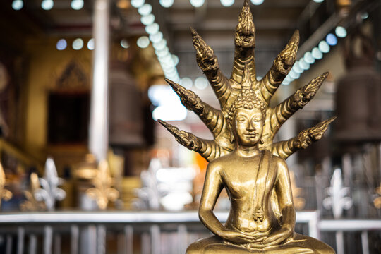 Seated Golden Buddha Statue under Nine-Headed Naga Protection in a Thai Temple.