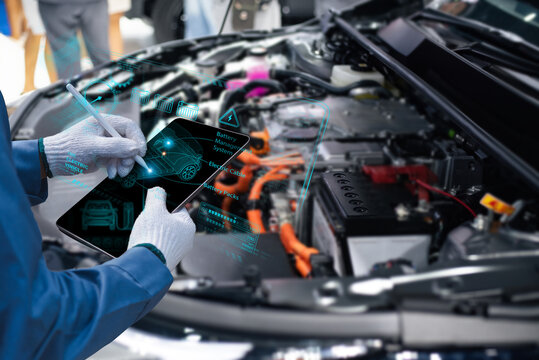 Close-up of a technician's hands using a digital tablet with a holographic augmented reality UI to diagnose an electric vehicle's engine and battery management system. Blurred car engine background.