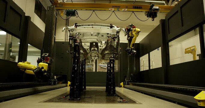 Automated robotic inspection cell performing precision measurement on white car body frame in automotive factory