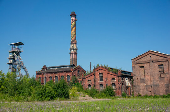 Hard Coal Mine (KWK Myslowice) was closed in 2008. Shaft hoist tower, smoke stack, old brick buildings, blue sky. Mysłowice, Poland.