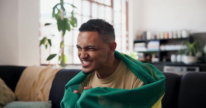 Victory, shout and football fan in home with flag, goal excitement or celebration in sports tournament. Supporter, watching soccer or hispanic man with game, score lead or winning cheer in Brazil.