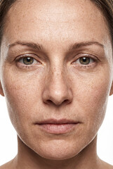 Obraz premium High-resolution close-up portrait of mature woman with natural skin texture, freckles and wrinkles. White background.