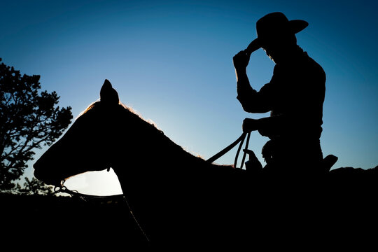 Cowboy Tipping Hat Silhouette on Horse Western Tradition Concept
