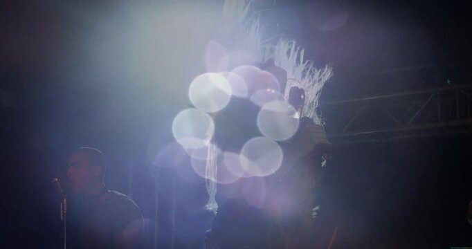 Female lead musician starting chord headbanging to beat lens flares drifting across music stage