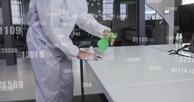 Cleaner sanitizing office table by spraying from green bottle and wiping with data overlays
