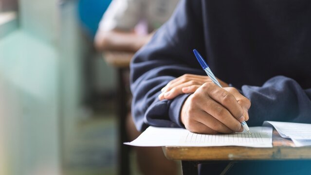 Close-up of Student Hand Holding Pen and Marking Answer Sheet in Exam Hall