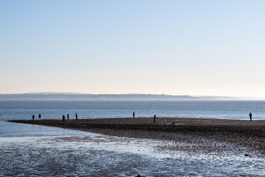 silhouette figures on the beach at Hill Head Meon Shore Hampshire England with The Isle of Wight in the background