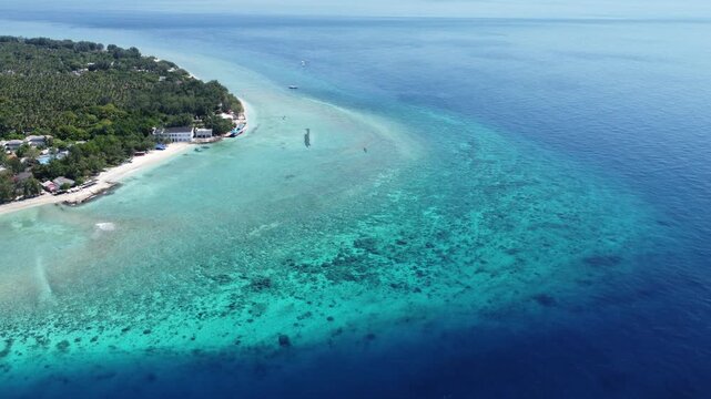 Aerial drone hovering then moving left above shallow turquoise water along Gili Trawangan coastline, Indonesia.