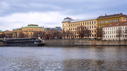 Fototapeta premium Ancient buildings in Prague's Old Town district, located along the banks of the Vltava River, seen from a tourist boat sailing its waters.