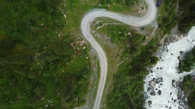 Aerial tilt-roll shot of a winding mountain serpentine road, metaphor for complex navigation, flexibility, and the nonlinear journey to success.