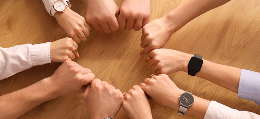 Fototapeta premium Business people putting hands together on wooden table, top view