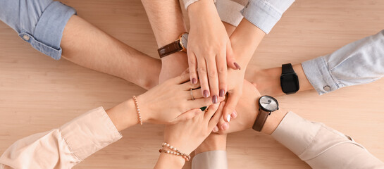 Group of people putting hands together on table, top view