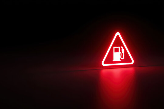 Glowing red fuel warning icon with petrol pump symbol in dark minimal background representing energy crisis, low fuel alert and rising gas costs