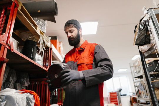 Worker inspecting material roll in industrial warehouse