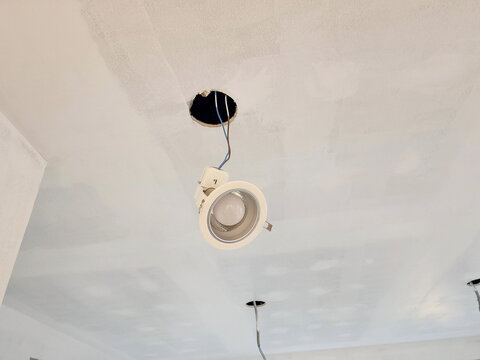 Recessed downlights are lights that hang from ceiling and are currently being installed or repaired. They are fixtures that provide downward illumination and use spring clips to attach to ceiling pane