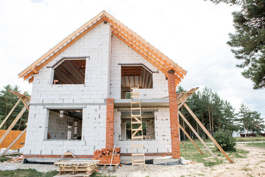 Contemporary home with exposed rafter system, roof lag installation in progress, light facade, European architectural style, active construction.